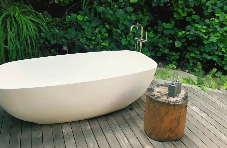Minimalist outdoor bathtub surrounded by greenery.